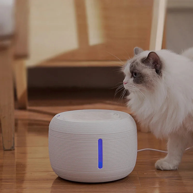 Fuente de agua para gatos de 2,5 L silenciosa con filtro y luz LED, con un gato bebiendo en casa